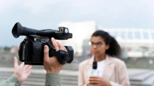 Professional video camera filming a female reporter during an outdoor corporate shoot by Corporate Filmmakers India.