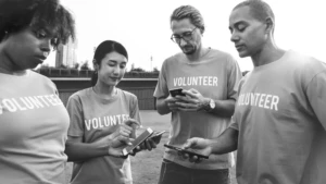 Black and white image of NGO volunteers using smartphones outdoors, teamwork for Development Sector Films and non-profit initiatives.