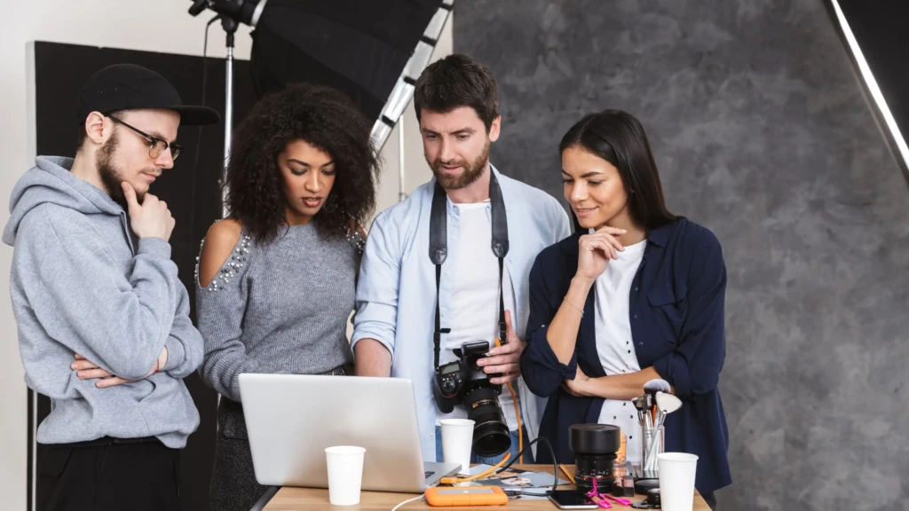 Creative team reviewing footage on laptop while planning corporate films focused on social sector storytelling and impact.