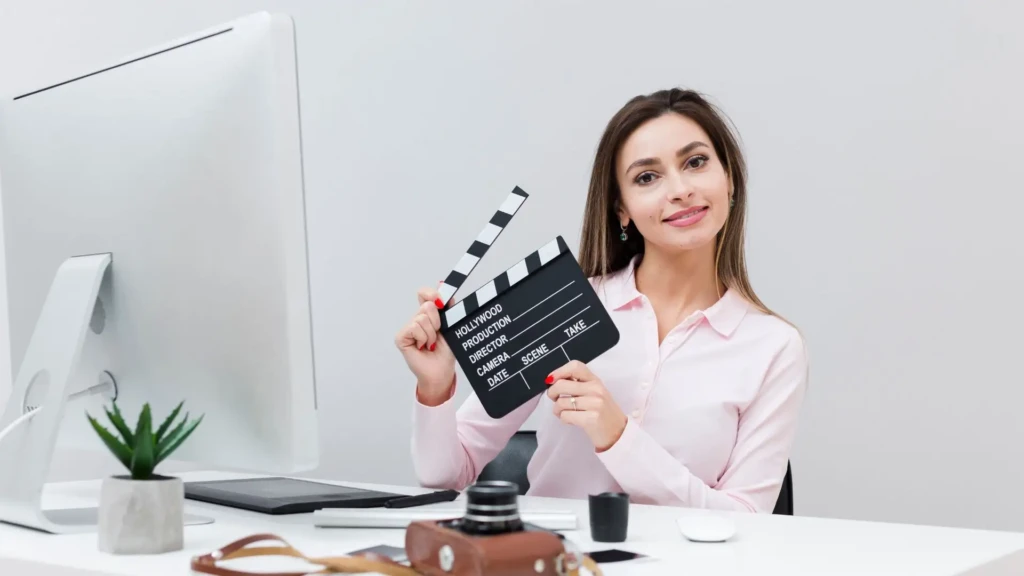 Corporate video production professional holding clapperboard at desk, symbolizing filmmaking challenges and planning work.