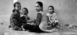 Four young girls sitting together, sharing a candid moment that reflects Humanitarian Photography in CSR Impact Reports