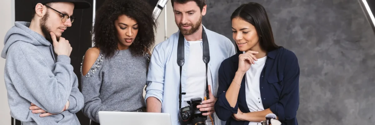 Creative team reviewing footage on laptop while planning corporate films focused on social sector storytelling and impact.