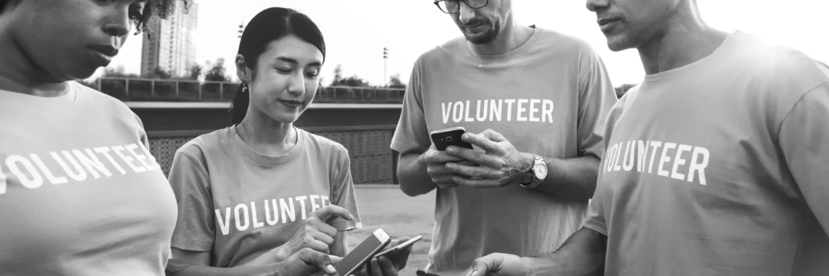 Black and white image of NGO volunteers using smartphones outdoors, teamwork for Development Sector Films and non-profit initiatives.