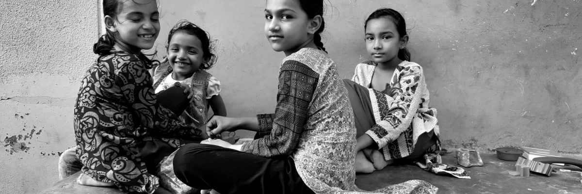 Four young girls sitting together, sharing a candid moment that reflects Humanitarian Photography in CSR Impact Reports